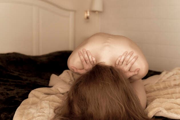 Nude young woman huddled on the bed at home model released Symbolfoto property released AFVF05960