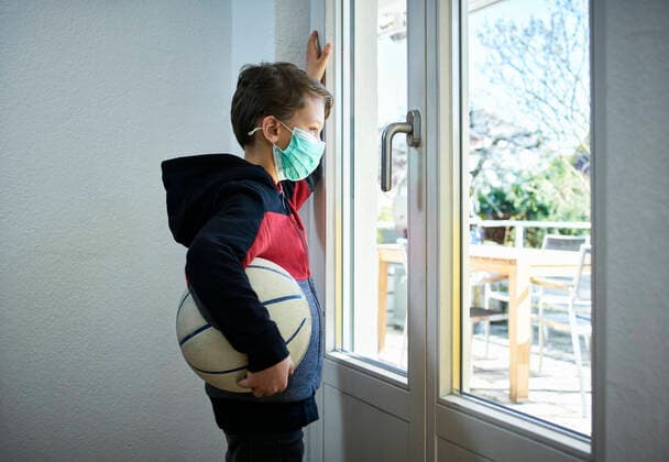 Sad boy with basketball and mask looking out of window model released Symbolfoto property released DIKF00405