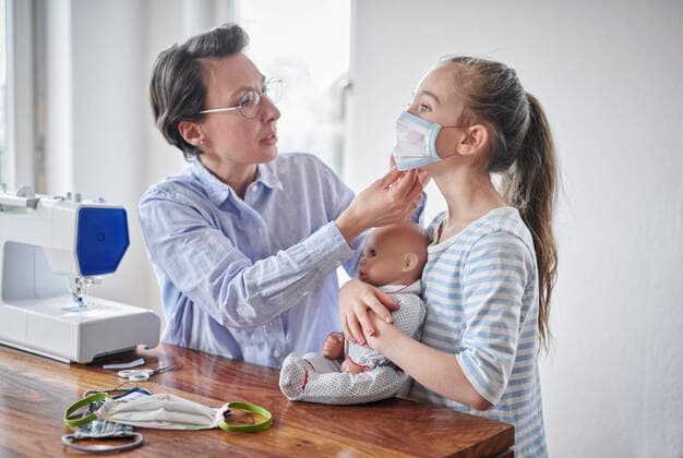 Mother sewing face masks for her daughter and her doll model released Symbolfoto property released DIKF00422