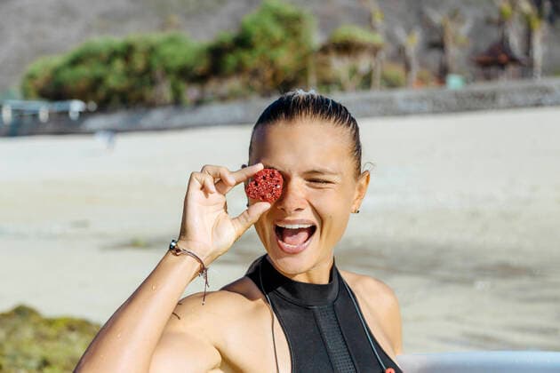 Portrait of female surfer holding stone on her eye model released Symbolfoto KNTF04496