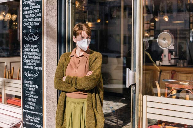 Woman wearing mask standing in front of her closed restaurant model released Symbolfoto MFF05146