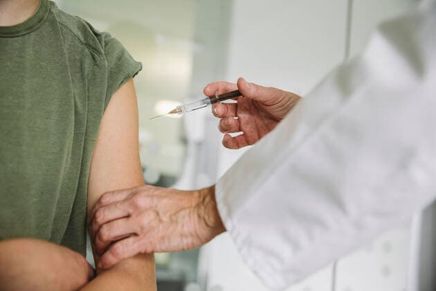 Doctor injecting vaccine into arm of teenager model released Symbolfoto property released MFF05510