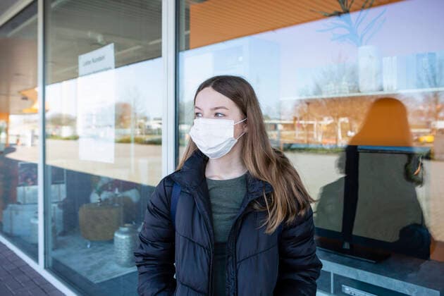 Girl with mask standing at closed shopping center model released Symbolfoto OJF00373