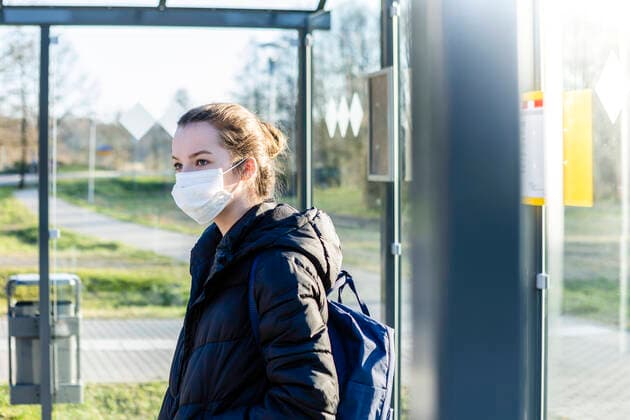 Portrait of a girl with mask waiting at bus stop model released Symbolfoto OJF00382