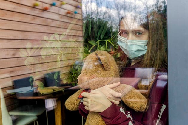 Portrait of girl with surgical mask and teddy bear behind window pane model released Symbolfoto property released SARF04513