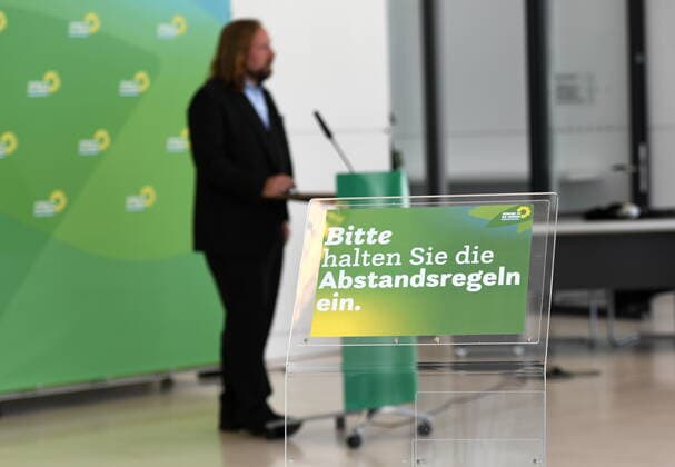 In front of the Bündnis 90 Die Grünen parliamentary group room in the Bundestag, there is a wall with the partys logos and a microphone There, members of the Bundestag give interviews and statements to the press A sign is currently informing the media representatives that they must observe the rules of distance In the background, parliamentary group chairman Dr Anton Hofreiter