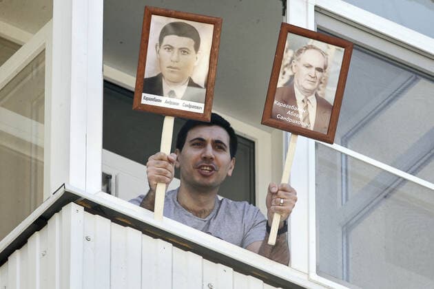 ROSTOV-ON-DON, RUSSIA - APRIL 25, 2020: A local man shows portraits of his relatives who fought in the 1941-1945 Great Patriotic War, as he listens to singers of the Song and Dance Ensemble of the Russian Army Southern Military District perform outside a block of flats to cheer up people who have to stay at home due to lockdown measures amid the pandemic of the novel coronavirus disease (COVID-19). The open-air concert is part of a series of concerts, which the military musicians plan to perform in various residential areas of the city ahead of the forthcoming 75th anniversary of Soviet Victory in the Great Patriotic War (part of WWII). Rostov-on-Don has been on lockdown since 31 March 2020. Valery Matytsin TASS  TS0D70B5