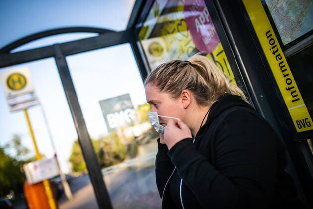 A woman puts on a mouth-nose mask at a BVG bus stop in Berlin From Monday, 27 April 2020, masks are mandatory in public transport Masks are mandatory in public transport