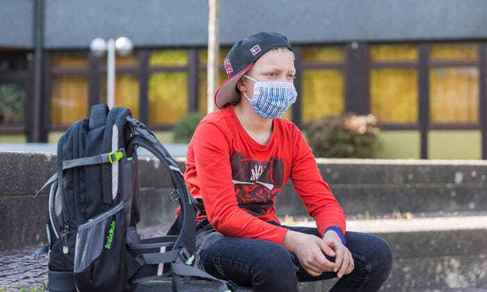 06 05 2020, Corona measures compulsory masks and school A boy with a mouth noses makeshift mask sits in the schoolyard This is how the new normality of our children from Bad Brückenau Bavaria Germany