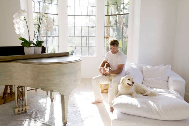 Creative Highlights Symbol Mid-Adult Man Playing Guitar in Living Room near Pet Dog,model released, Symbolfoto  Copyright: x JamiexWilliamsx xGlasshousexImx ghi-novo03516