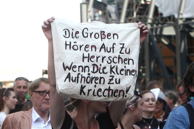An authorized demonstration against the corona related infection protection law and the associated restrictions on freedom took place in the city center of Cologne, North Rhine-Westphalia, Germany A demonstrator holds a poster with an inscription that says the big ones stop ruling when the small ones stop crawling up