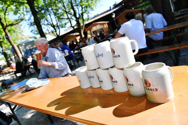 Beer mugs are standing on a beer table in the background a man is drinking a Weissbier Reopening Paulaner beer garden at Nockherberg in the course of the Corona loosening on 18 05 2020 in Munich