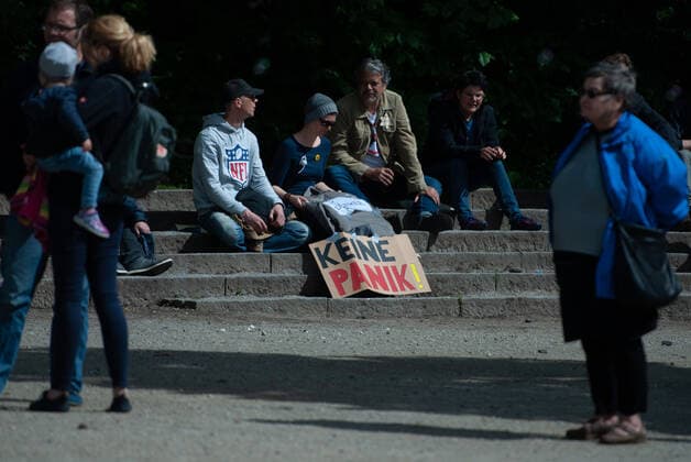 Coronavirus, demonstration against Corona measures Four demonstrators sit on stone steps, in front of them a banner with the inscription Dont panic , one demonstrator has a Jewish star on his jacket, on it stands unvaccinated, on 23 05 2020 in Flensburg, at the harbour, at the tip of the harbour