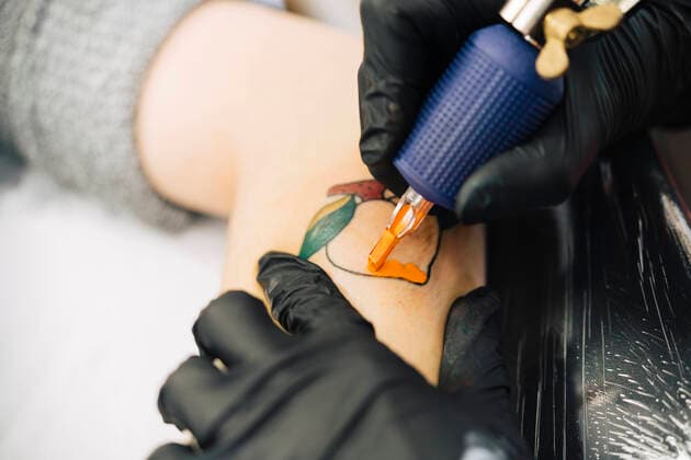 Female tattooist tattooing a peach on a woman s arm model released Symbolfoto property released JSMF01544