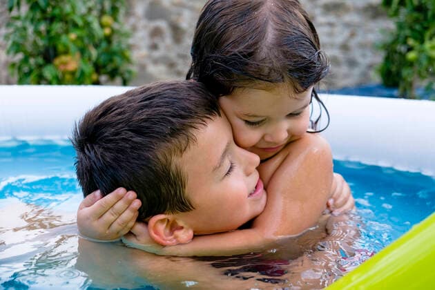 Brother and his little sister hugging each other in swimming pool model released Symbolfoto MGIF00928