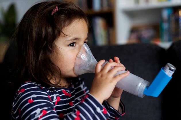 Close-up of asthmatic girl using inhaler in living room at home model released Symbolfoto property released VABF02888