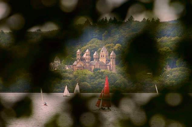 The abbey Maria Laach in the Eifel with sailing boats at a regatta on the Laach lake