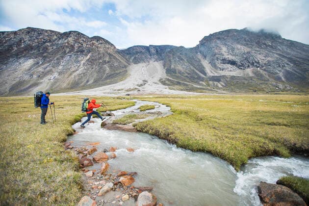 Backpackers cross rushing river at a narrow point, Akshayak Pass. Pangnirtung, NU, Canada CR_JDIP200331-320846-01,model released, Symbolfoto