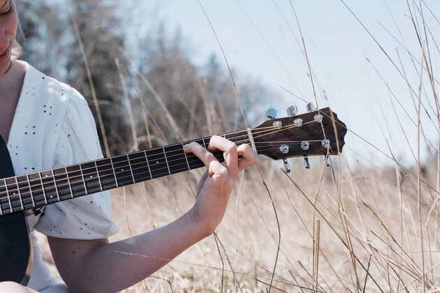 Tag der Musik am 21. Juni view of woman s hand playing guitar in a field in summer Norrtälje, Stockholm County, Sweden CR_RABE200430-361956-01,model released, Symbolfoto