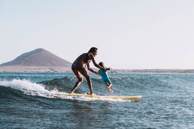 Full view of surfer mother surfing a small wave with her son Santa Cruz de Tenerife, CN, Spain CR_SEVI200406D-197096-01,model released, Symbolfoto