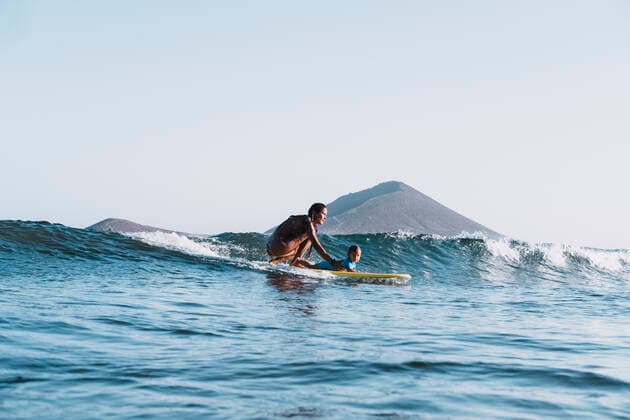 IMAGO Creative: Lokalhelden - Jugendsportbildung Pulled back view of mother and son surfing a small wave Santa Cruz de Tenerife, CN, Spain CR_SEVI200406D-197105-01,model released, Symbolfoto