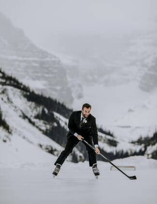 Just married groom skates with hockey stick on Lake Louise, Alberta Lake Louise, AB, Canada CR_SSNF200422A-341522-01,model released, Symbolfoto