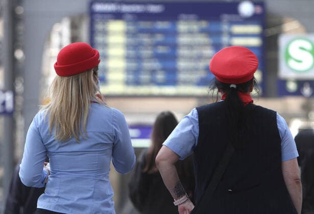 DB Deutsche n Bahn AG train attendants walk in front of the scoreboard at Frankfurt central station, Hessen Germany