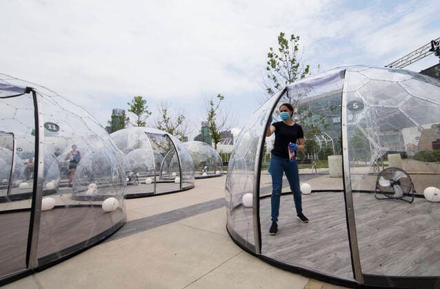 (200623) -- TORONTO, June 23, 2020 -- A staff member (R) cleans a yoga dome after use in Toronto, Canada, on June 22, 2020. A new pop-up event called Hot Yoga has been held in Toronto from June 21 to July 31. People can take part in yoga classes inside their own private dome to prevent the spread of COVID-19. (Photo by Xinhua) CANADA-TORONTO-COVID-19-YOGA DOMES ZouxZheng 