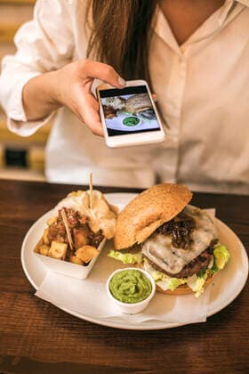 Midsection of woman photographing fresh meal served in plate on table at restaurant model released Symbolfoto ACPF00557