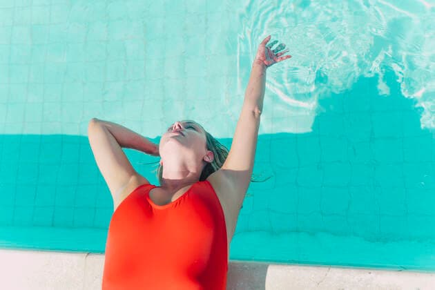 Woman wearing red swimsuit lying at the poolside model released Symbolfoto property released ERRF03663