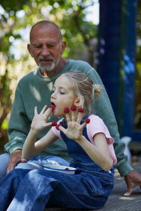 Grandfather and granddaughter eating raspberries on terrace in garden model released Symbolfoto property released MCF00854