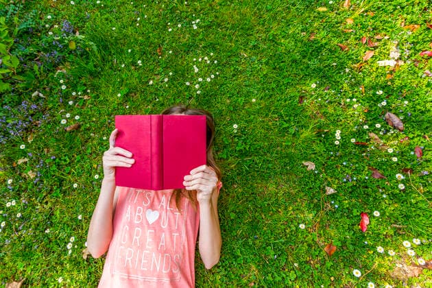 Girl lying on meadow reading a book, top view model released Symbolfoto property released SARF04566