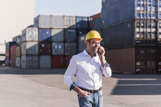 IMAGO Creative: Business, Inflation und Lieferketten Portrait of businessman on the phone in front of cargo containers model released Symbolfoto UUF20409