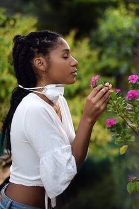 Young woman takes face mask off to smell the flowers Colombia, Valle del Cauca, Cali CR_RBIG200611-428882-01 ,model released, Symbolfoto