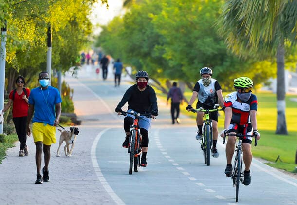 (200702) -- DOHA, July 2, 2020 (Xinhua) -- People wearing face masks walk and cycle along a street in Doha, capital of Qatar, on July 1, 2020. (Photo by Nikku Xinhua) QATAR-DOHA-COVID-19 