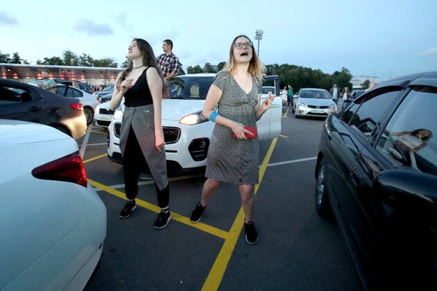 MOSCOW, RUSSIA - JULY 4, 2020: Young people dance outside their car during a drive-in concert by The Hatters gypsy folk rock band in Luzhniki. The concert, in which the sound is broadcast to the cars via FM radio, is part of LIVE&DRIVE, a series of live drive-in concerts organised by the TCI concert agency and SAV Entertainment Group during the pandemic of the novel coronavirus disease (COVID-19). Vyacheslav Prokofyev TASS  TS0DF270