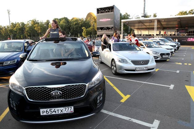 MOSCOW, RUSSIA - JULY 4, 2020: Young people at a drive-in concert by The Hatters gypsy folk rock band in Luzhniki. The concert, in which the sound is broadcast to the cars via FM radio, is part of LIVE&DRIVE, a series of live drive-in concerts organised by the TCI concert agency and SAV Entertainment Group during the pandemic of the novel coronavirus disease (COVID-19). Vyacheslav Prokofyev TASS  TS0DF274