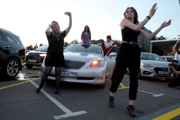 MOSCOW, RUSSIA - JULY 4, 2020: Girls dance during a drive-in concert by The Hatters gypsy folk rock band in Luzhniki. The concert, in which the sound is broadcast to the cars via FM radio, is part of LIVE&DRIVE, a series of live drive-in concerts organised by the TCI concert agency and SAV Entertainment Group during the pandemic of the novel coronavirus disease (COVID-19). Vyacheslav Prokofyev TASS  TS0DF28A