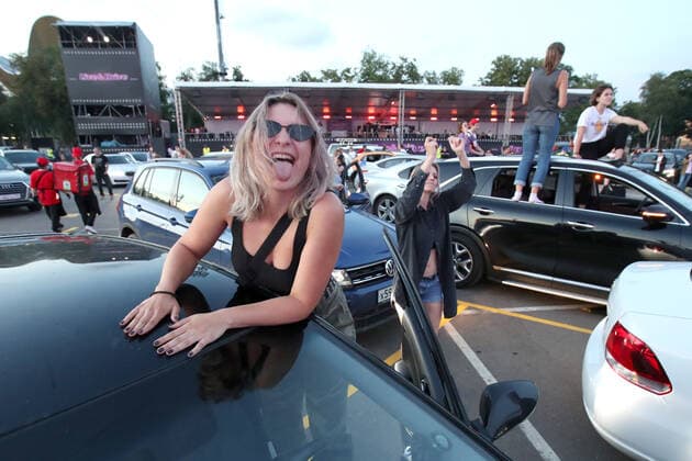 MOSCOW, RUSSIA - JULY 4, 2020: Young people at a drive-in concert by The Hatters gypsy folk rock band in Luzhniki. The concert, in which the sound is broadcast to the cars via FM radio, is part of LIVE&DRIVE, a series of live drive-in concerts organised by the TCI concert agency and SAV Entertainment Group during the pandemic of the novel coronavirus disease (COVID-19). Vyacheslav Prokofyev TASS  TS0DF28F
