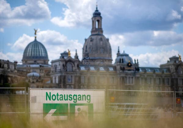 16 July 2020 Dresden Saxony, Elbe meadows A poster with the inscription Emergency exit is hung on a building fence, behind it the historical old town of Dresden with the Frauenkirche is visible