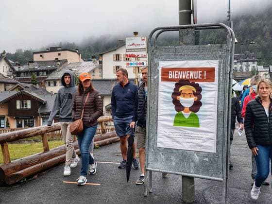 July 19, 2020, Chamonix, Chamonix Mont Blanc, France: Pedestrians in Chamonix, France walk past a sign with a masked face on it. In this region, the vast majority of visitors, locals, and workers go without masks or wear them improperly. The French Conseil Scientifique has warned of a second wave and the country will be imposing a stricter mask regulation. If it will be accepted remains to be seen. Chamonix France - ZUMAb160 20200719_zbp_b160_002 Copyright: xSachellexBabbarx