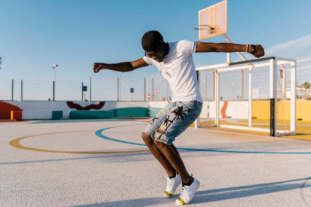 Carefree young man dancing in sports court against clear sky model released Symbolfoto EGAF00299