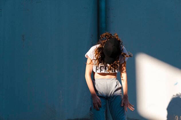 Female hip-hop dancer dancing against white wall during sunny day model released Symbolfoto JMPF00174