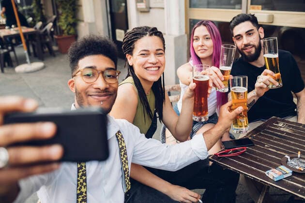 Happy friends holsing beer glasses and taking a selfie outdoors at a bar model released Symbolfoto MEUF00804