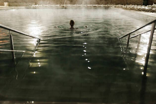IMAGO Creative: Internationaler Frauenmonat, Gesundheit, Frauen in der Menopause Mid adult woman swimming in hot pool at tourist resort during night model released Symbolfoto MRRF00080
