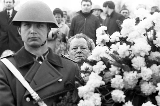 Bundeskanzler Willy BRANDT schaut zwischen einem NVA Soldaten und einem Blumengesteckt hindurch, bei der Kranzniederlegung im ehemaligen Konzentrationslager Buchenwald, anlaesslich eines Treffens mit DDR Ministerpraesident Willi Stoph am 19.03.1970 in Erfurt; Schwarzweissaufnahme; *** Chancellor Willy BRANDT looks through a NVA soldier and a flower arrangement while laying a wreath in the former concentration camp Buchenwald on the occasion of a meeting with GDR State Premier Willi Stoph on 19 March 1970 in Erfurt.