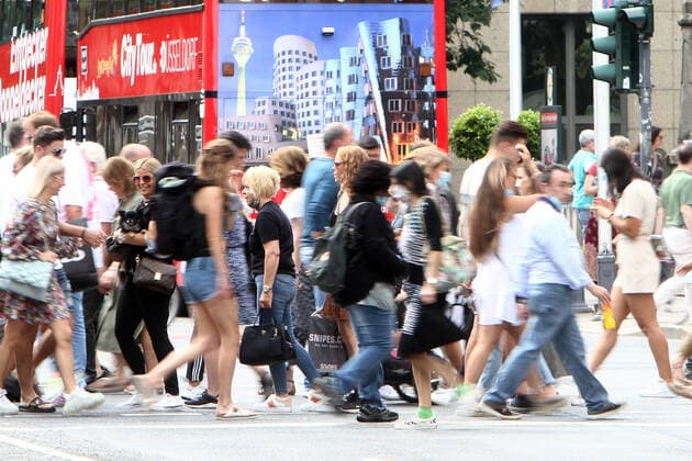Pedestrians cross a cross street of the shopping street Königsallee in the city centre of Düsseldorf, which after the relaxation of the protective measures and the reopening of shops appears again as it did before the corona crisis with a large crowd of people who largely do not keep the required minimum distance from each other, North Rhine-Westphalia, Germany