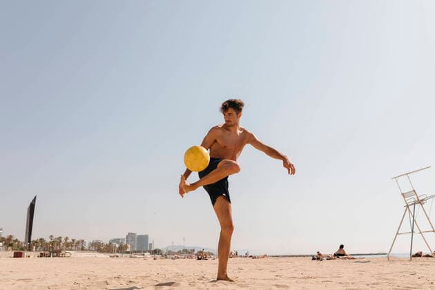 IMAGO Creative: Sommer Sport - Strand Shirtless male athlete playing with ball at beach against clear sky on sunny day model released Symbolfoto VABF03117
