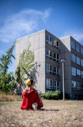 IMAGO Creative: Gesellschaft, Armut 31. Juli 2020: Leipzig (Sachsen), Stadtteil Gruenau: Ein Kind sitzt vor einem Plattenbau in Leipzig-Gruenau. *** 31 July 2020 Leipzig Saxony , Gruenau district A child sits in front of a prefabricated concrete building in Leipzig Gruenau