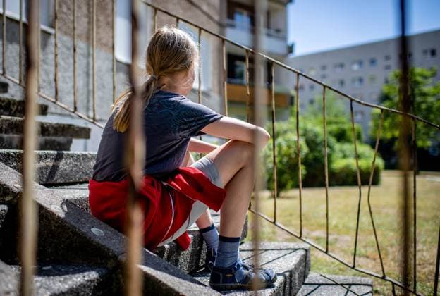 31. Juli 2020: Leipzig (Sachsen), Stadtteil Gruenau: Ein Kind sitzt vor einem Plattenbau in Leipzig-Gruenau. *** 31 July 2020 Leipzig Saxony , Gruenau district A child sits in front of a prefabricated concrete building in Leipzig Gruenau